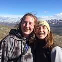 Hannah and Becca smile together on top of a mountain.